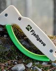 Hvit og grønn knivsliper med Fjellgave-logo på en mosekledd trestamme.